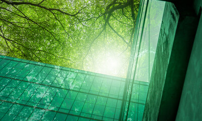 Eco-friendly building in the modern city. Sustainable glass office building with trees for reducing...