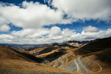 A Winding Mountain Roads and Rugged Landscape Under Dramatic Clouds