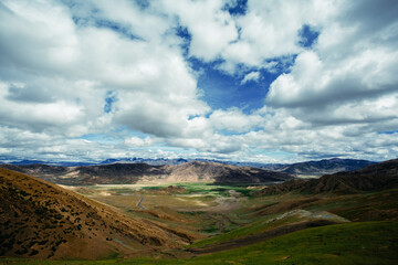 A Majestic Mountain Valley with Rolling Hills and Dramatic Clouds