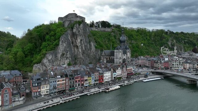 Ascending drone shot of the riverfront buildings and Notre Dame de Dinant Church in Dinant, Belgium
