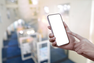 Close-up of a woman hand holding a smartphone white screen at building background. Transparent mobile screen mockup.