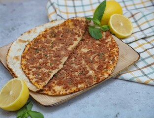 Close-up of traditional lahmacun served with fresh lemon and herbs on a wooden board
