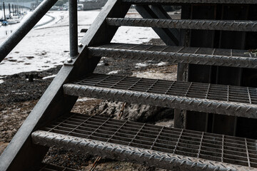 Closeup shot of metal stairs descending to a beach at low tide