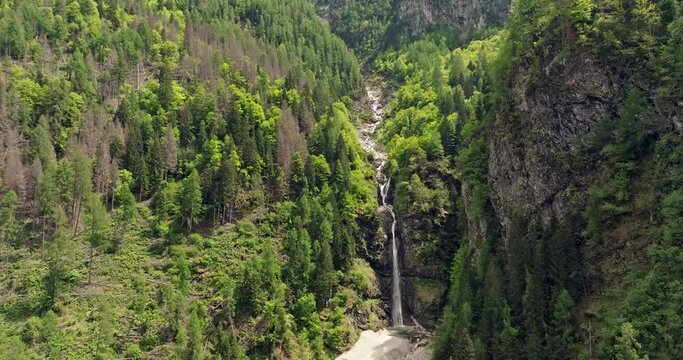 Aerial view of a waterfall in the Dolomite Alps, Italy. The natural landscape of the river flows through the canyon and falls down in the mountains. High quality 4k footage