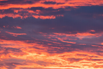 Fototapeta premium Orange-red colored cloudy sky after sunset, cloud formation, evening sky, sunset.