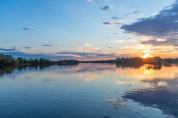 A breathtaking view of a tranquil spring river with a breathtaking sunset reflecting off the still water.