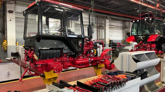 Tractor Manufacture plant. Assembly line inside the agricultural machinery factory. Installation of parts on tractor body. Tractor Works made on factory. Assembly line in Production plant.
