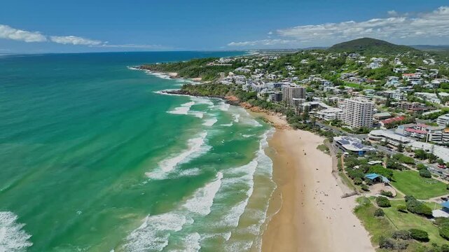 Aerial scenery of Coolum Beach with coastal buildings and green cliffs in Sunshine Coast, Australia