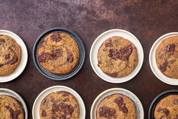 Homemade chocolate chip cookies in ceramic plates on rustic background.