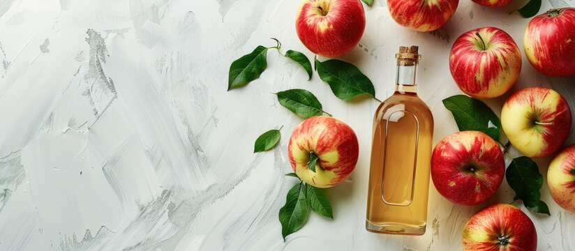 Fresh red apples and apple cider vinegar in a glass bottle on a light background.