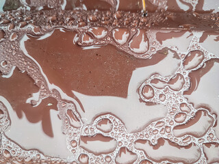 Raindrops under plastic wrap on brown surface