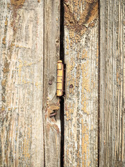 Texture of a wooden plank fence with vertical wood strips, brown wooden fence connection with door hinge