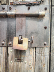 Texture of a wooden plank fence with vertical wood strips, brown wooden fence door with padlock