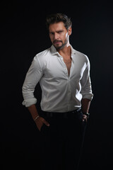 Handsome man in white shirt with hands in his pockets standing and looking to the camera