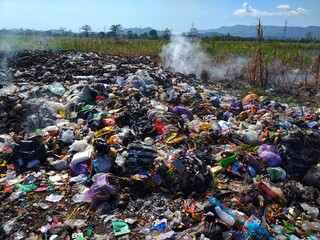A burning garbage heap in a field, emitting smoke. Suitable for environmental pollution, waste...