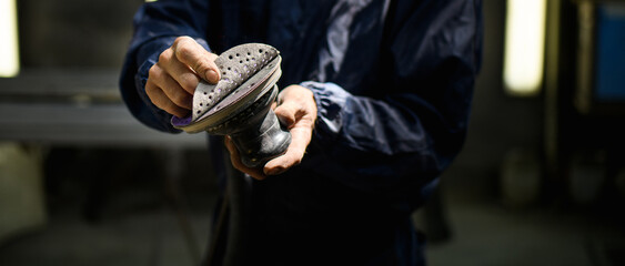 Banner shot of mechanic holding sander in garage 