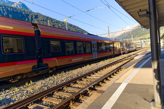 Golden SOB train at railway station of mountain village Airolo on a sunny late summer day. Photo taken September 10th, 2023, Airolo, Switzerland.