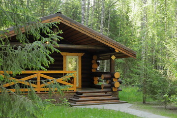 Naklejka premium Log house in the summer woods surrounded by pine and birch trees.