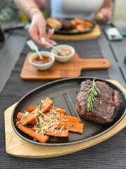 Grilled Steaks with spices rosemary and pepper on wooden board on black background.