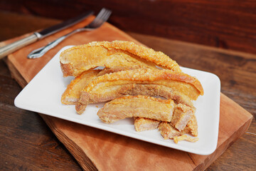 Thai food. Crispy fried pork belly cut into pieces on a wooden table.
