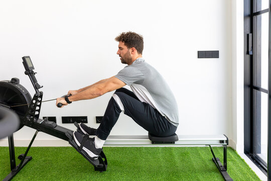 Man exercising on a rowing machine in a bright gym