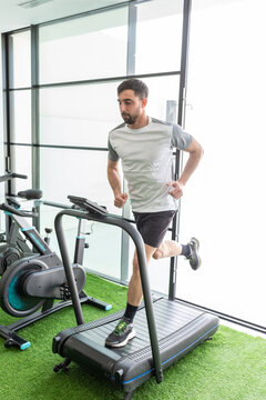 Man running on treadmill in bright gym environment