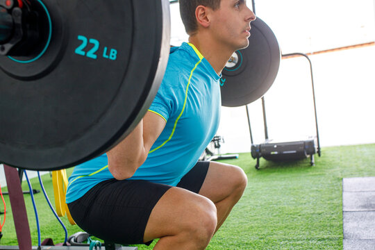 Determined man performing a squat with weights in a gym