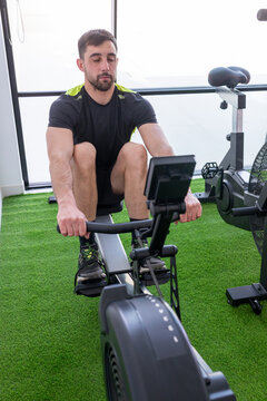 Young man training on a rowing machine in a modern gym