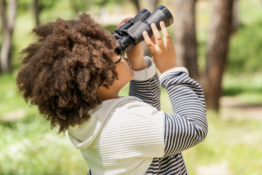 Young girl using binoculars in a sunny park setting