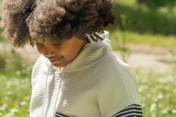 Young girl deep in thought at a sunny park
