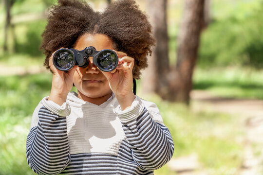 Young girl exploring nature with binoculars in park