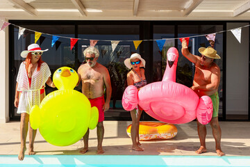 Joyful seniors celebrating with pool floats