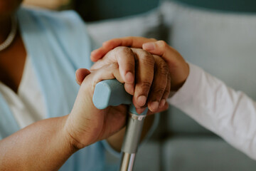 Hand of young nurse carefully and lovely caressing mature African American womans hand as try to...