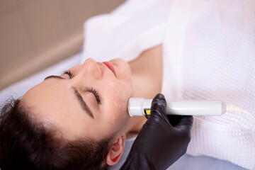 Closeup of face of beautiful relaxing girl undergoing hardware cosmetology procedure in spa