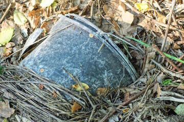 garbage from a piece of a broken black plastic bucket stands on the gray ground on the street