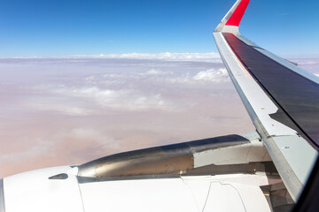 View from an airplane window to the wing and cumulus clouds