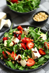Summer salad with strawberries, arugula, Camembert cheese and pine nuts.