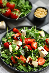 Summer salad with strawberries, arugula, Camembert cheese and pine nuts.