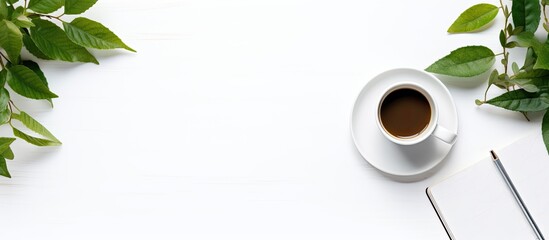 An office desk viewed from above with items like a notebook, book, supplies, pencil, leaf, and coffee cup arranged neatly on the white surface, forming a visually appealing copy space image.