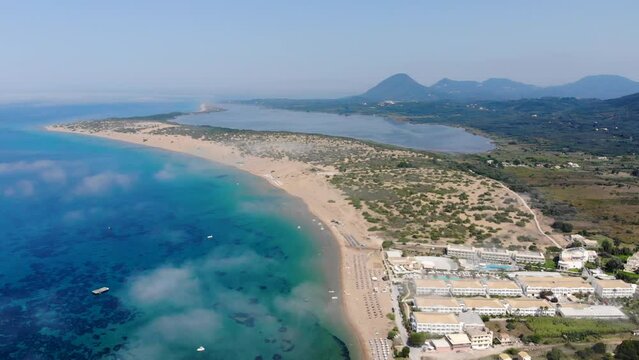 Aerial footage of the beautiful small town known as St George South, Greek city of Corfu Greece, showing the Issos Beach with mountains in the background