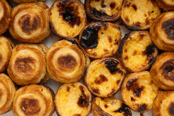 Several traditional Portuguese egg tart dessert Pasteis Pastel de nata over white marble background.