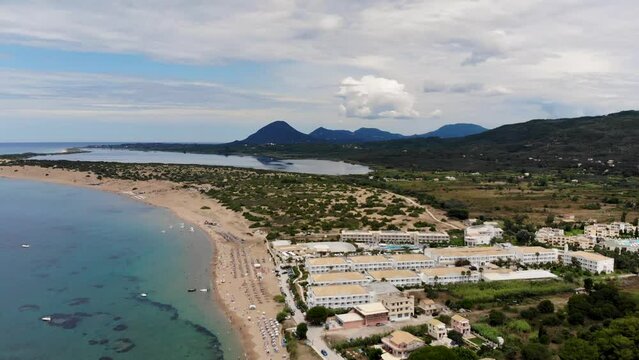 Aerial footage of the beautiful small town known as St George South, Greek city of Corfu Greece, showing the Issos Beach with mountains in the background
