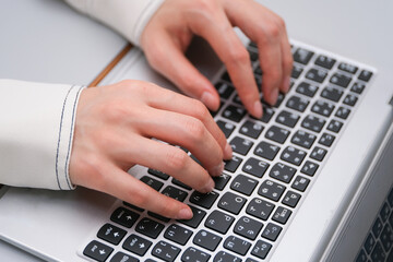 ノートパソコンのキーボードを打つ女性の手のクローズアップ