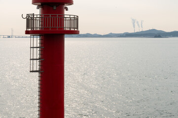 View of the red beacon against the sea during sunset