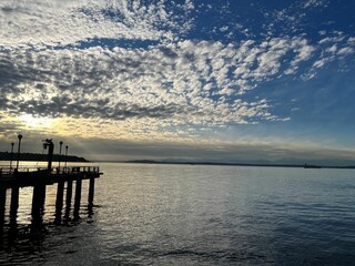Obraz premium Scenic view of a pier at sunset with a dramatic sky over a calm body of water