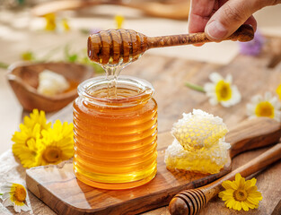 Natural organic honey in glass jar, honey dipper and honeycombs are near. Natural food background.