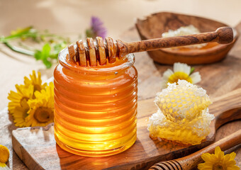 Natural organic honey in glass jar, honey dipper and honeycombs are near. Natural food background.