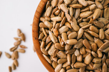 Sunflower seeds in wooden bowl isolated on white background
