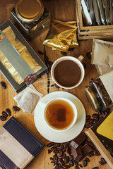 Cocoa bean tea packet in a white glass on a wooden table with chocolate chunks next to it surrounded by seeds.