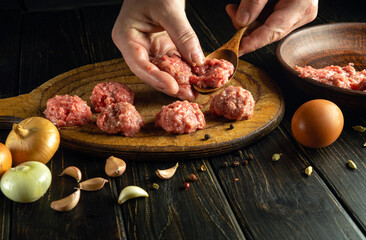 The cook uses his hands to form meatballs from minced meat to prepare a delicious lunch.